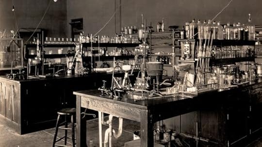 An old-fashioned laboratory filled with various glassware, bottles, and scientific instruments on wooden tables, illuminated by overhead lights.