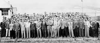 A large group of men in formal attire posing together outdoors, possibly representing a historical event or organization.