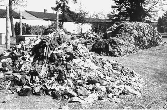 Piles of discarded clothing stacked outdoors, with trees and buildings in the background.