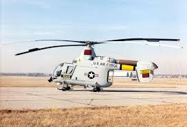 A military helicopter parked on an airstrip with its rotor blades visible.