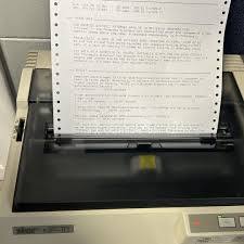 An old printer producing a page with text from a continuous form paper.
