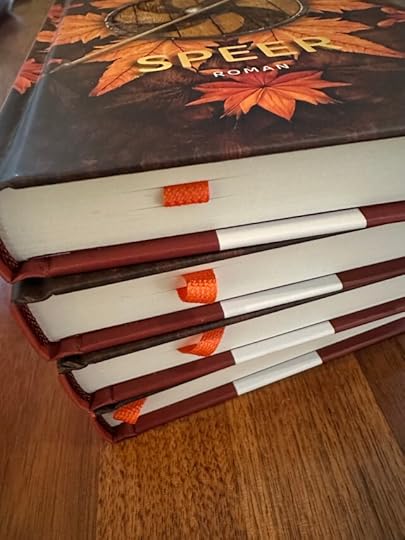 Close in view of four books showing a woven, rich orange book ribbon peeking out from each