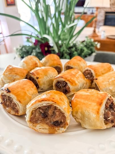 Golden baked sausage rolls with date and rosemary arranged on a white serving platter