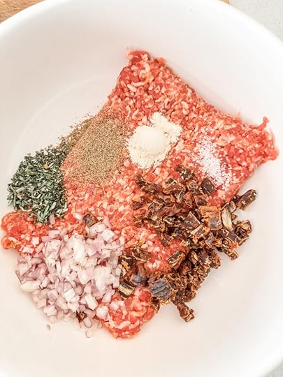 The spices and medjool dates with the ground sausage, prior to mixing