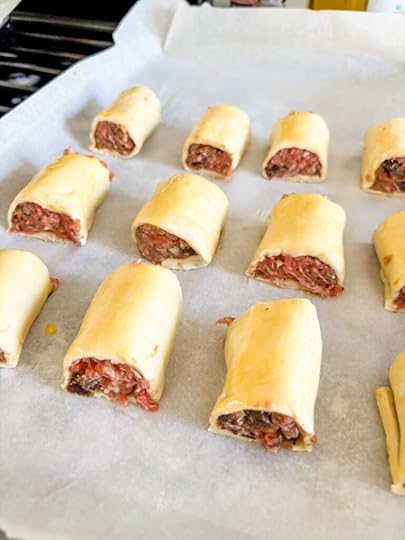 The prepared sausage rolls, ready for baking on a parchment lined baking sheet