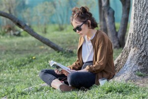 Woman sitting on grass, reading a book.
