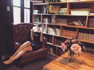Woman on couch covers her face with a book.