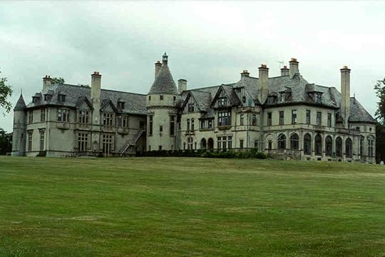 A grand mansion featuring intricate architectural details, large windows, and multiple chimneys, set against a grassy landscape under a cloudy sky.
