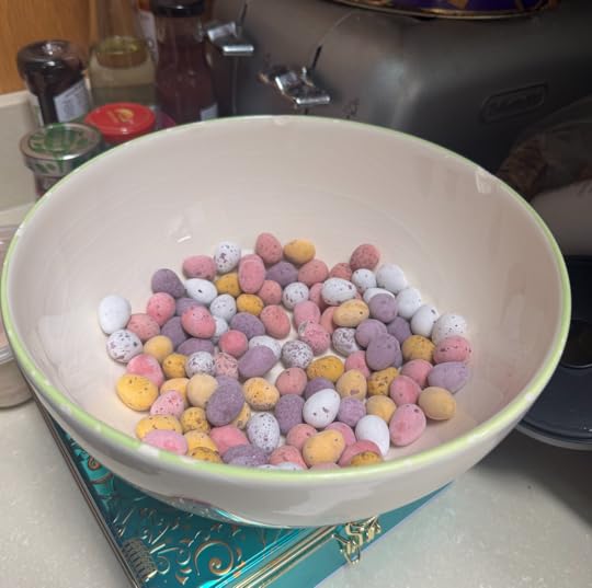 A cream porcelain bowl with dozens of multicoloured mini eggs inside.