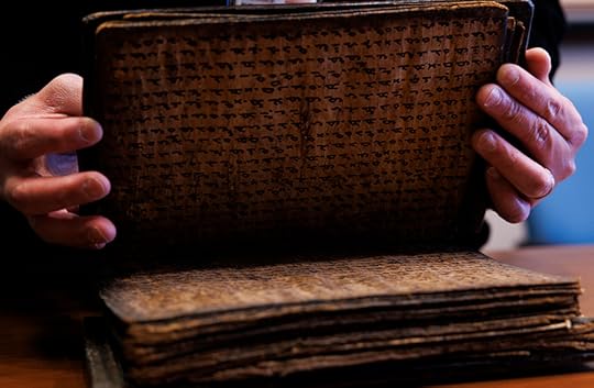 Medium close up of 19th century book opened partway to show the brown bark pages and writing in black ink.