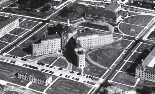 Aerial view of a large institutional complex featuring multiple buildings and landscaped grounds.