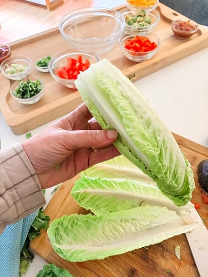 Marie holding up a bundle of romaine lettuce hearts with the board in the background