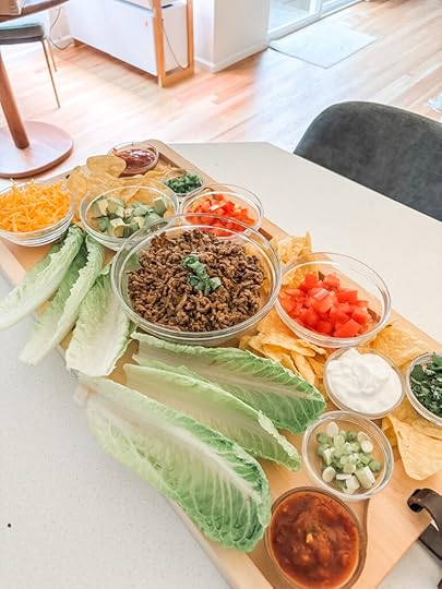 Low-carb taco board with romaine lettuce cups, seasoned beef, and colorful toppings arranged on a large wooden serving board
