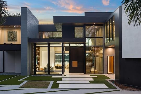 Modern home exterior wit glass front, lake view and conference room visible inside.