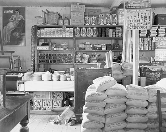 Well lit interior photo of a neatly kept country store in rural Alabama. Canned good and kerosene lamps are on many shelves; sacks of grain are on the floor. 