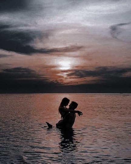 This may contain: two people in the water at sunset, one is holding the other's head