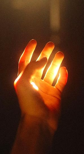 This may contain: a person holding their hand up in the air with light coming from it's fingers
