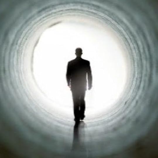 This may contain: a man in a suit and hat is walking through a dark tunnel with light coming from the end
