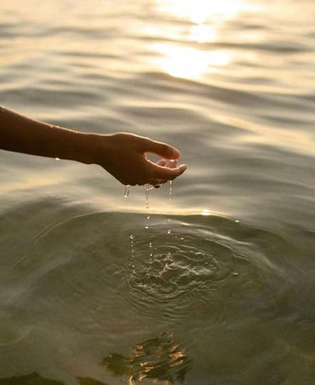 This may contain: a person's hand reaching for something in the water