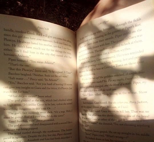 This may contain: an open book sitting on top of a wooden table next to a leafy tree