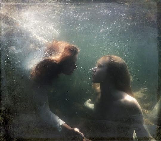 This may contain: two people are in the water with their backs to each other and looking at each other