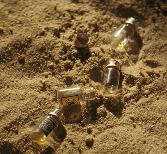 This may contain: three empty glass bottles sitting in the sand