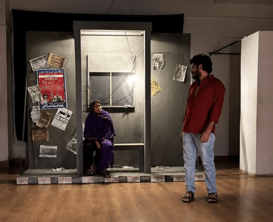 A tense scene from Gehra Samandar, Neele Khaab shows Raana Kazmi seated inside a dimly lit Karachi-style bus stop while Yogeshwar Karera stands nearby in silence, capturing the emotional isolation and intimacy of the play.