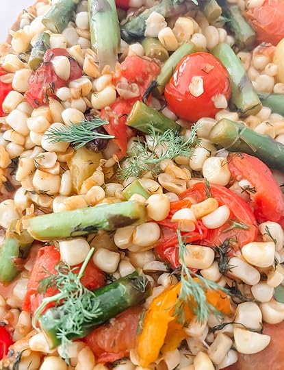 Close-up of springtime succotash with bright green asparagus, golden corn kernels, and burst cherry tomatoes garnished with fresh dill