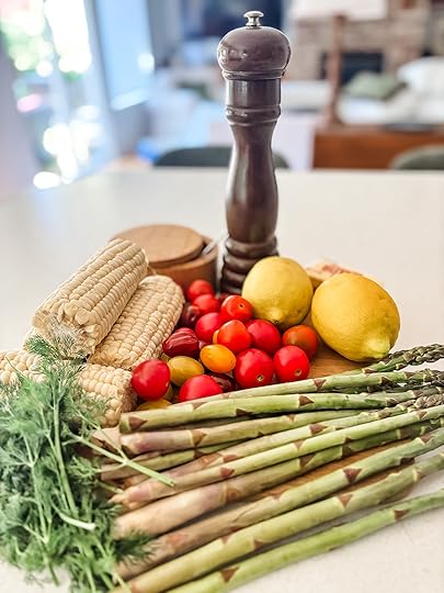 Fresh ingredients for springtime succotash including corn on the cob, asparagus stalks, cherry tomatoes, fresh dill, lemon, and butter