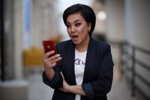 Woman reading on phone looks shocked and surprised.