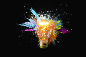 Image is of a lightbulb that is on and is exploding with colorful sprays of light