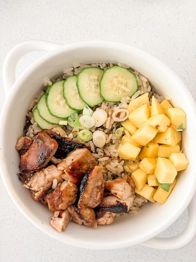 Mango chicken coconut rice bowl topped with fresh mango, sliced cucumber, scallions, and cilantro over coconut lime jasmine rice