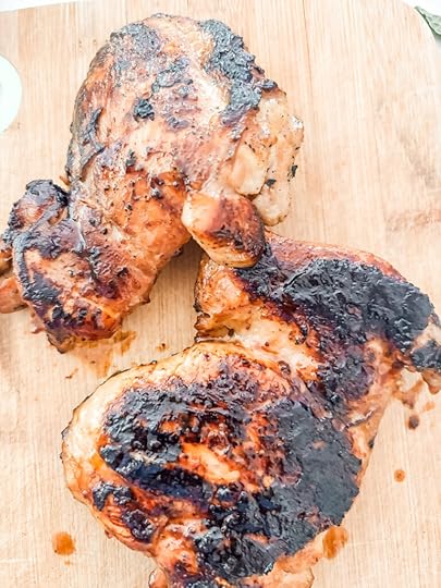 The marinated and broiled chicken thighs on a wooden cutting board