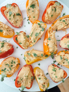 Colorful stuffed mini bell peppers filled with cream cheese and hot pepper jelly arranged on a white serving platter