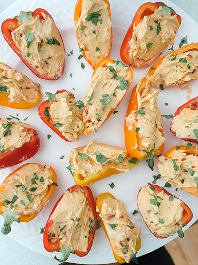 Colorful stuffed mini bell peppers filled with cream cheese and hot pepper jelly arranged on a white serving platter 