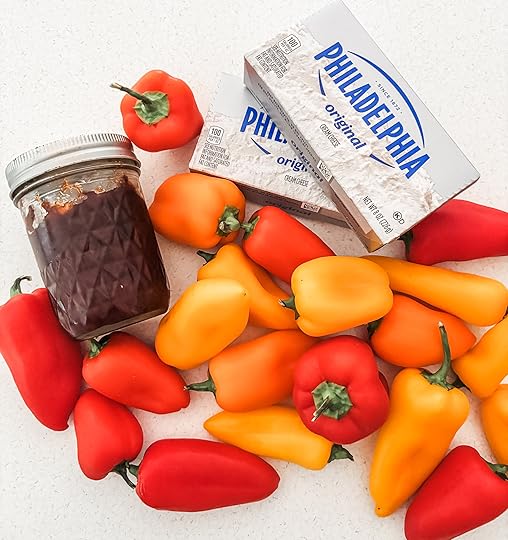 Three ingredients for stuffed mini pepper appetizers — a bag of mini bell peppers, a block of cream cheese, and a jar of hot pepper jelly on a kitchen counter