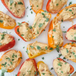 Colorful stuffed mini bell peppers filled with cream cheese and hot pepper jelly arranged on a white serving platter