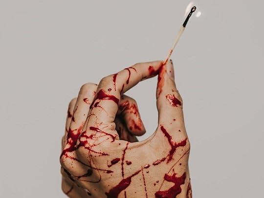 A hand covered in blood splatter holding a burning match
