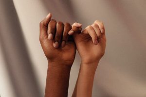 two hands with linked pinky fingers