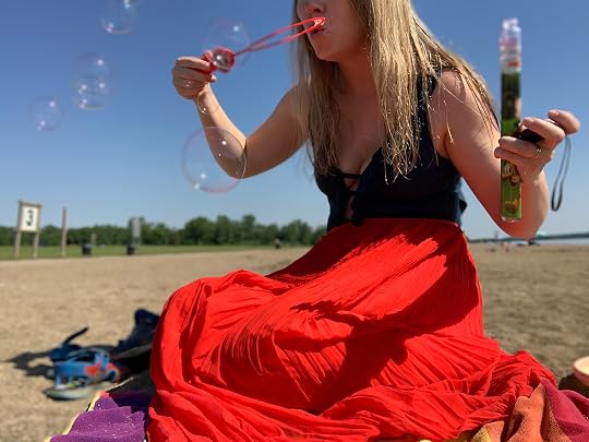 Person blowing soap bubbles at the beach on a sunny day