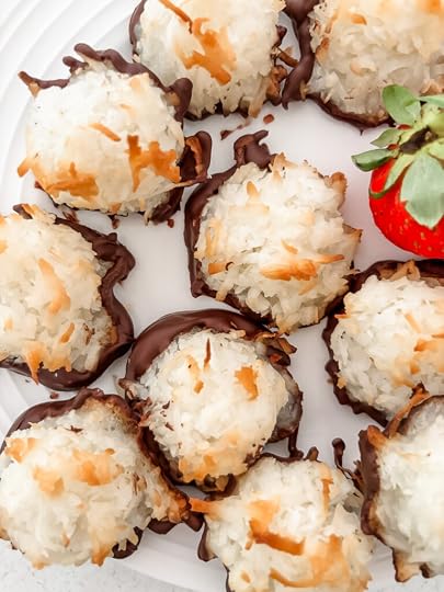 Close-up of a chocolate-dipped coconut macaroon showing its golden toasted exterior and dark chocolate base with strawberries