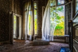 Abandoned room, windows open, curtains blowing in the wind.