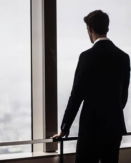 This may contain: a man standing in front of a window looking out at the city