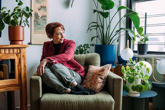 Martha surrounded by plants looking out the window.