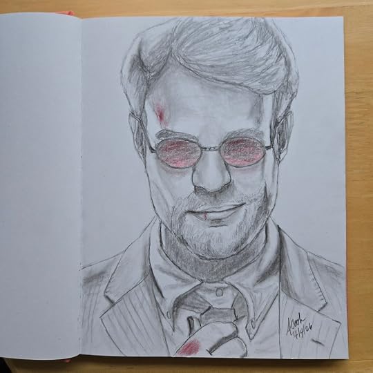 A sketchbook is open to a page featuring a pencil sketch of the actor Charlie Cox as Matthew Murdock from the the TV series, 