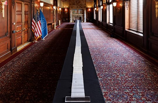 An extremely long white scroll of paper lies unrolled down the middle an ornate room in the Library. It extends so far that the end cannot be seen.
