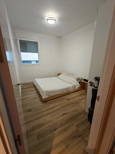 Photo of a bare but tidy bedroom, with a double bed and a wardrobe almost out of shot