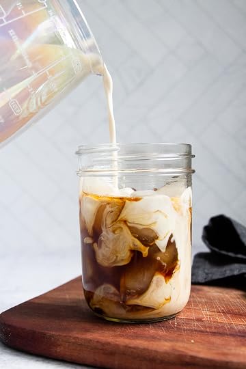 Creamer being poured into a jar of cold brew coffee