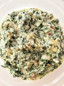 Creamed kale and carrot tops in a rich parmesan cream sauce served in a white bowl