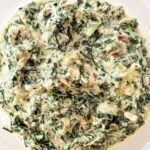 Creamed kale and carrot tops in a rich parmesan cream sauce served in a white bowl
